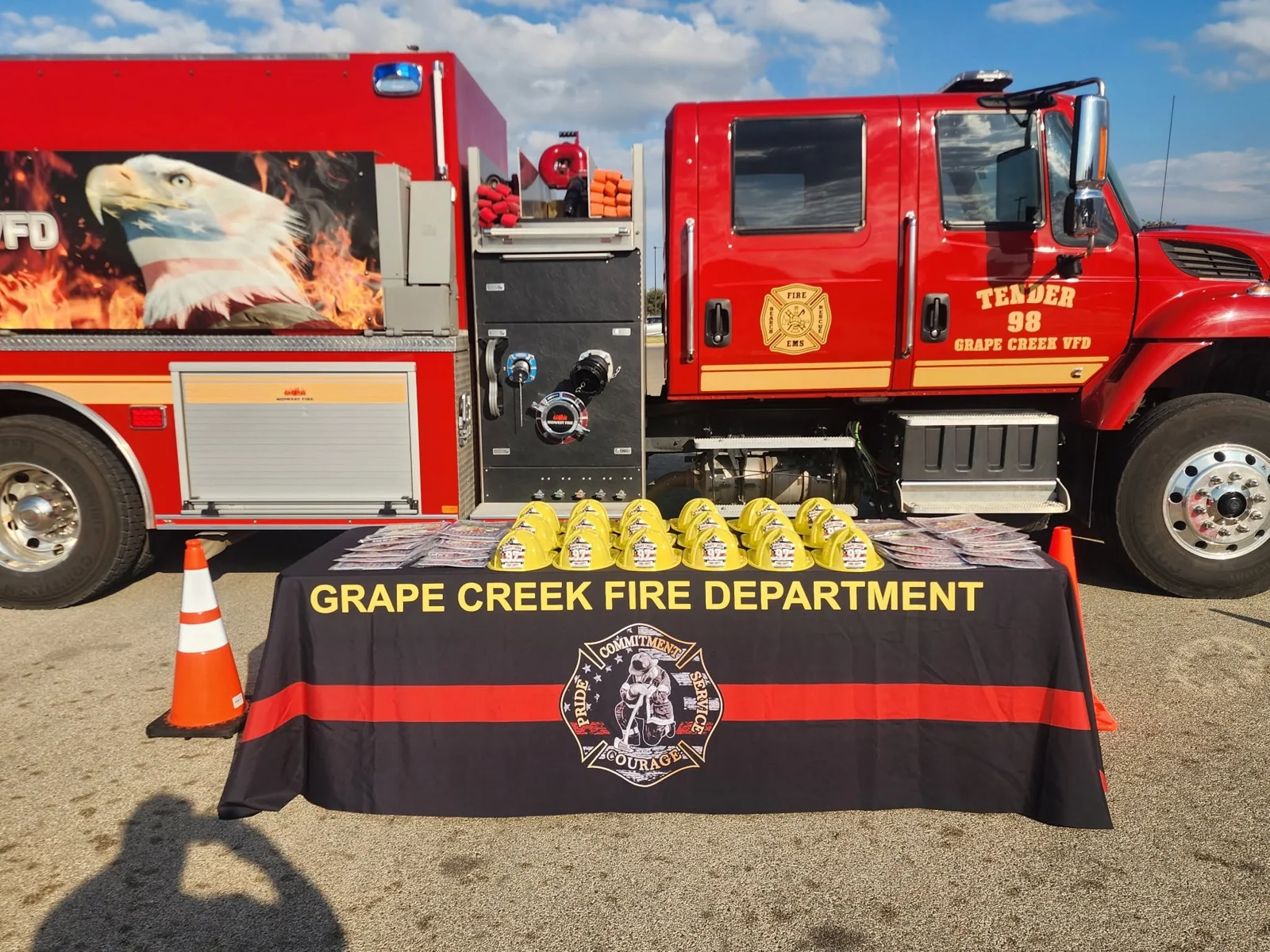 Grape Creek VFD Tender 98 behind a community outreach table with junior firefighter helmets